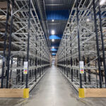 Pallställ med svarta stolpar, gula påkörnignsskydd och galvade bärbalk